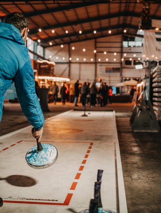 Mann wirft Eisstock auf mobiler Indoor-Eistockbahn